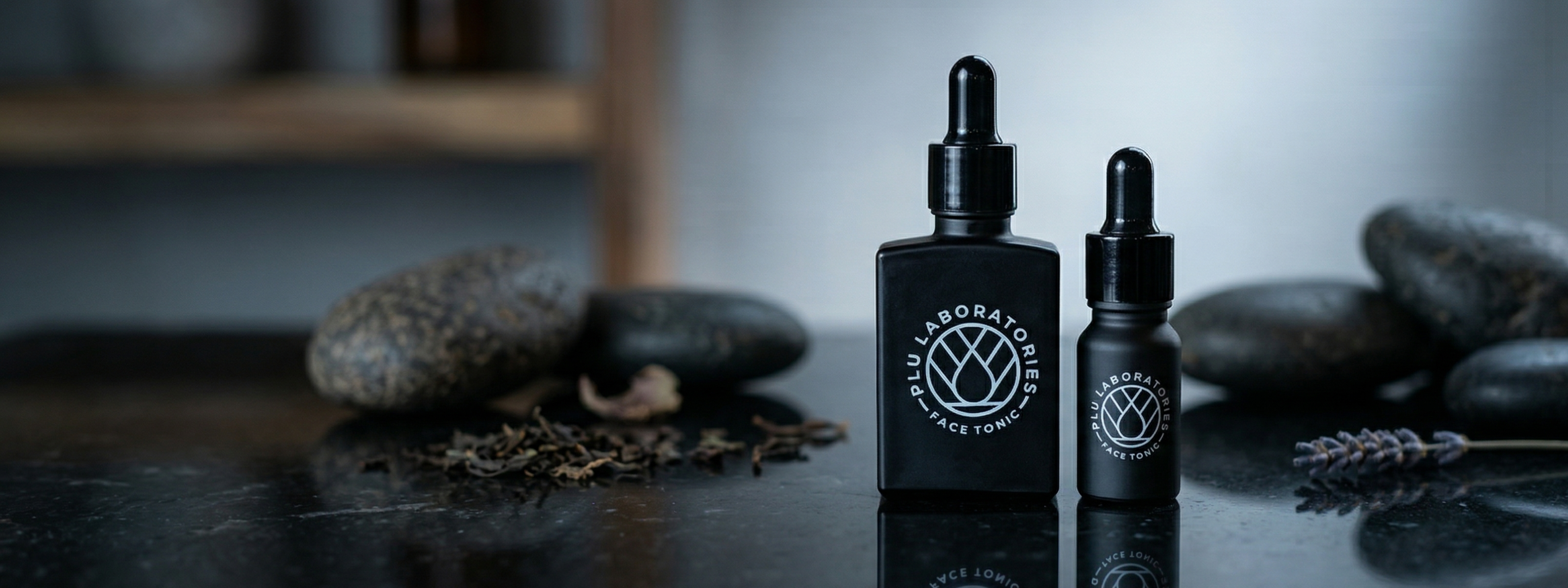 Two black bottles with droppers on a reflective surface with stones and plants in the background.